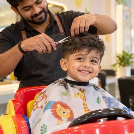 A smiling young boy having a haircut on a colourful kids’ chair