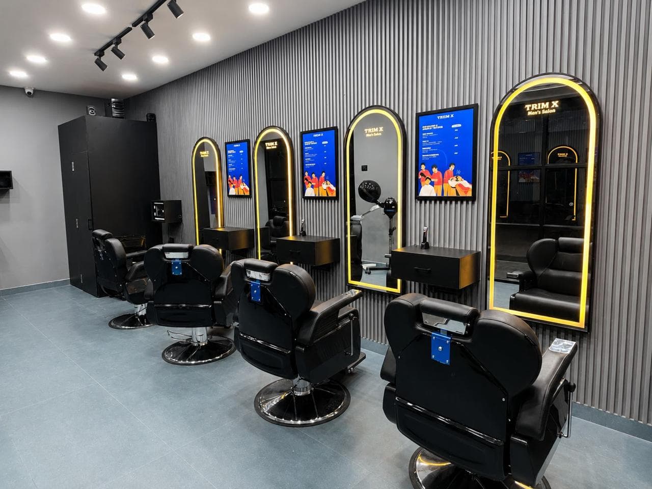 A TrimX salon interior: four styling chairs along a wall of lit arch mirrors, matte-black counters, and the opening onto the kiosk check-in area beyond.